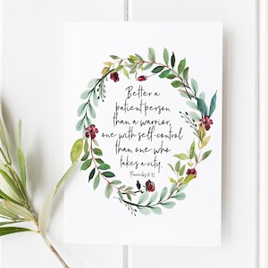 May include: A white rectangular print featuring a watercolour wreath of green leaves and small dark red flowers surrounding the black text: Better a patient person than a warrior, one with self-control than one who takes a city. Proverbs 16:32.