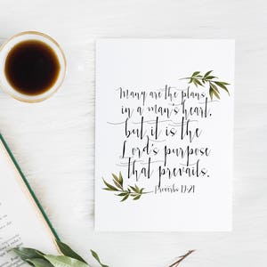 May include: A white printable card with a black and green leafy design. The card features a quote from Proverbs 19:21, "Many are the plans in a man's heart, but it is the Lord's purpose that prevails."