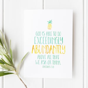 May include: A white rectangular print featuring a watercolor pineapple icon at the top. The text reads: GOD IS ABLE TO DO EXCEEDINGLY ABUNDANTLY ABOVE ALL THAT WE ASK OR THINK. EPHESIANS 3:20. The lettering uses green and yellow watercolor-style ink.