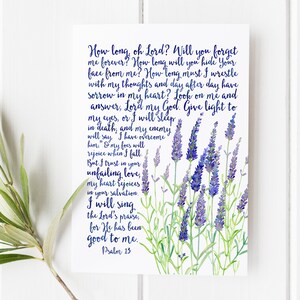 May include: A white card with the text of Psalm 13 in dark blue script. Watercolor lavender sprigs in shades of purple and green are on the right side of the card. The card is on a white wooden surface.