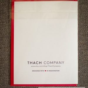 May include: A white card with red edging, featuring the text "THACH COMPANY" in black, followed by the website address "www.etsy.com/shop/ThachCompany". Below this, it reads "DESIGNED WITH &hearts; IN WASHINGTON". The card is in a clear plastic sleeve.