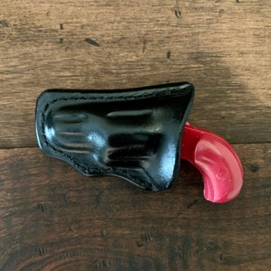 May include: A black leather holster with a red plastic toy gun inside.