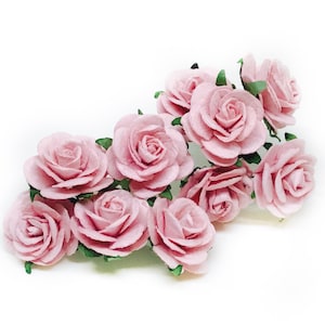 May include: A cluster of delicate pink paper roses with green leaves. The roses are arranged in a loose, cascading pattern, creating a romantic and whimsical feel.