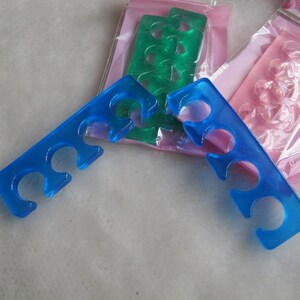 Op de afbeelding: Twee blauwe plastic teenspreiders voor het aanbrengen van nagellak. De spreiders hebben vijf gleuven voor elke teen.