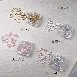 Puede incluir: Cuatro pequeños frascos llenos de piedras de cristal en forma de corazón en varios colores, incluyendo dorado, rosa, iridiscente y transparente. Los frascos están etiquetados como BJ87-1, BJ87-2, BJ87-3 y BJ87-4. El texto 4+6+10MM también es visible en la imagen.