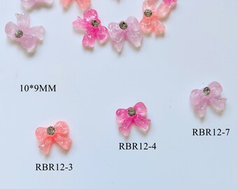 May include: Assortment of 10 pink and white resin bows with rhinestones, measuring 10mm x 9mm.  RBR12-3, RBR12-4, RBR12-7.