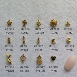 以下が含まれることがあります： 12個の金色の金属製のネイルアートチャームの詰め合わせ。チャームには、カメ、天使、ハート、矢印、ブドウの房、三日月、渦巻き、花、三角形、弓矢、装飾的なデザイン、釘が含まれています。チャームのサイズは約2〜9ミリメートルです。