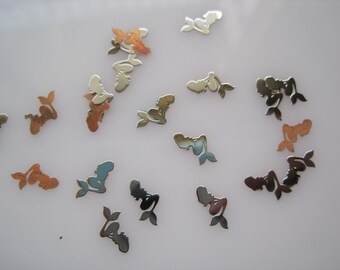 May include: Assortment of silver and gold mermaid-shaped charms. The charms are scattered on a white surface.