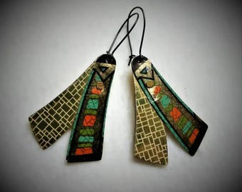 May include: A pair of gold and black earrings with geometric patterns and turquoise and orange accents. The earrings are made of metal and have a dangling design.