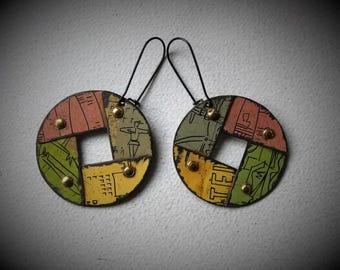 May include: A pair of earrings made from repurposed materials. Each earring is a circle with a square cut out of the center. The circles are made of different colored paper and have a gold and black finish. The earrings are attached to black wire hooks.