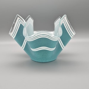 May include: A teal blue glass vase with white stripes. The vase has a wavy, ruffled design.