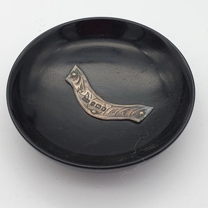 May include: A black lacquer tray with a silver and gold decorative trim. The trim is shaped like a crescent moon and has a floral design.