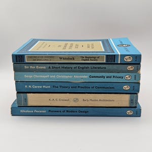 Puede incluir: Una pila de seis libros de bolsillo azules con títulos de texto blanco. Los libros son de la serie Pelican History of England e incluyen títulos como "The Beginnings of English Society", "A Short History of English Literature", "Community and Privacy", "The Theory and Practice of Communism", "Early Muslim Architecture" y "Pioneers of Modern Design".