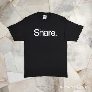 May include: Black t-shirt with the word "Share" printed in white on the front.