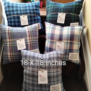 May include: Plaid shirt pillows in various colors, each measuring 18 x 18 inches. The pillows are made from repurposed shirts and tied with twine, with tags attached. The text on the tag reads "Made from a shirt I used to wear. Think of me there."