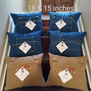 May include: Six decorative pillows made from denim and khaki-colored overalls, each measuring 18 x 15 inches. The pillows feature the pockets, straps, and hardware of the original garments, with tags attached. The pillows are arranged on a staircase.