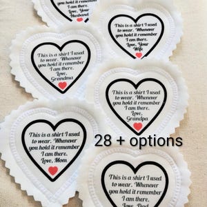 May include: White heart-shaped fabric patches with a scalloped edge. Each patch has a black heart outline with text and a red heart. Text includes phrases like "This is a shirt I used to wear."