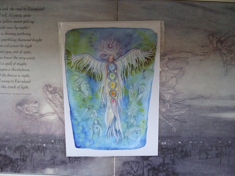 May include: A watercolor painting of a winged figure with a halo, surrounded by smaller figures. The central figure has a long, flowing tail and is adorned with seven colorful circles, possibly representing chakras. The background is a soft blue with hints of green.