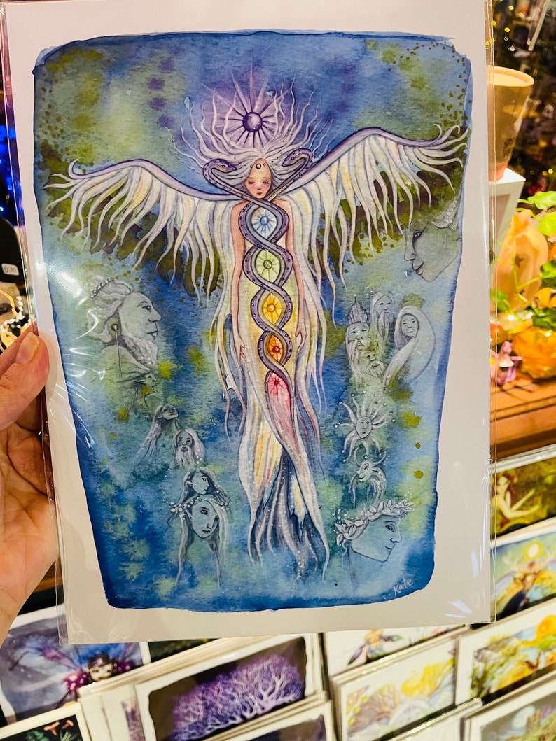 Puede incluir: Una pintura de acuarela de una mujer con alas y una serpiente de colores arco&iacute;ris envuelta alrededor de su cuerpo. La mujer est&aacute; rodeada de otras figuras y s&iacute;mbolos, incluyendo un sol y una luna. La pintura est&aacute; sobre un fondo blanco.
