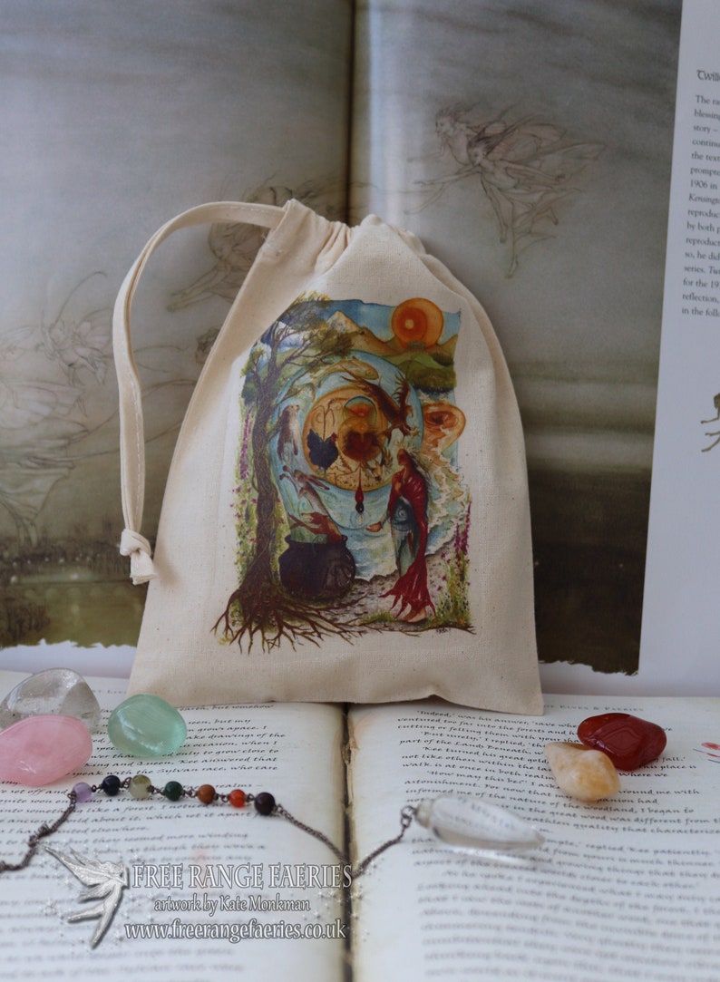 May include: A small, white drawstring bag with a colorful illustration of a fairy scene. The bag is sitting on a book with a crystal necklace and several colorful stones.