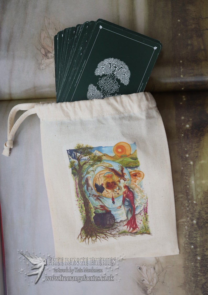 May include: A white canvas bag with a drawstring closure, containing a deck of cards with a green back. The cards feature a white illustration of a tree with a Celtic knot design. The bag has a colorful illustration of a scene with a tree, a woman, and a cauldron. The text "FREE RANGE FAERIES" is printed on the bag, along with the website "www.freerangefaeries.co.uk".