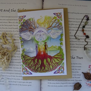 May include: A watercolor illustration of a tree with a rainbow-colored trunk and roots. The tree is surrounded by a white bird with wings spread. Two figures stand at the base of the tree, one male and one female. The illustration is on a white card with a brown border. The text "Elf-shot and the Sidhe" is written at the top of the card.