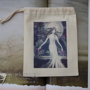 Puede incluir: Una bolsa de algod&oacute;n blanco con cord&oacute;n de ajuste que tiene una imagen impresa de una mujer con cabello largo y oscuro de pie en un paisaje iluminado por la luna. La imagen est&aacute; rodeada por un borde blanco. La bolsa tiene el texto "FREE RANGE FAERIES" y "artwork by Kate Monkman" impreso en la parte delantera.