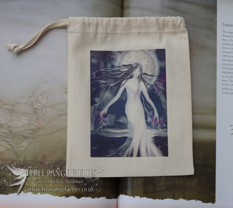 Puede incluir: Una bolsa de algod&oacute;n blanco con cord&oacute;n de ajuste que tiene una imagen impresa de una mujer con cabello largo y oscuro de pie en un paisaje iluminado por la luna. La imagen est&aacute; rodeada por un borde blanco. La bolsa tiene el texto "FREE RANGE FAERIES" y "artwork by Kate Monkman" impreso en la parte delantera.