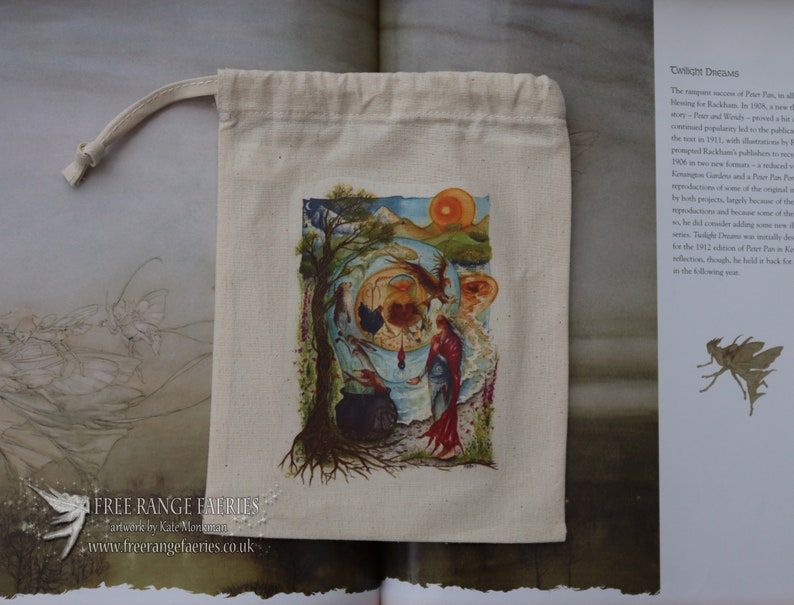May include: A white cotton drawstring bag with a colorful illustration of a fairy scene. The illustration features a fairy, a cauldron, a tree, and a red sunset. The bag has the text "FREE RANGE FAERIES" and "artwerk by Kate Monkman" printed on it.