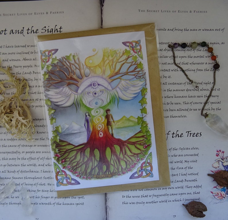 May include: A watercolor painting of a tree with rainbow colored rings around the trunk. The tree has large wings and is surrounded by a mountain range and a body of water. The painting is on a card with a Celtic knot border.