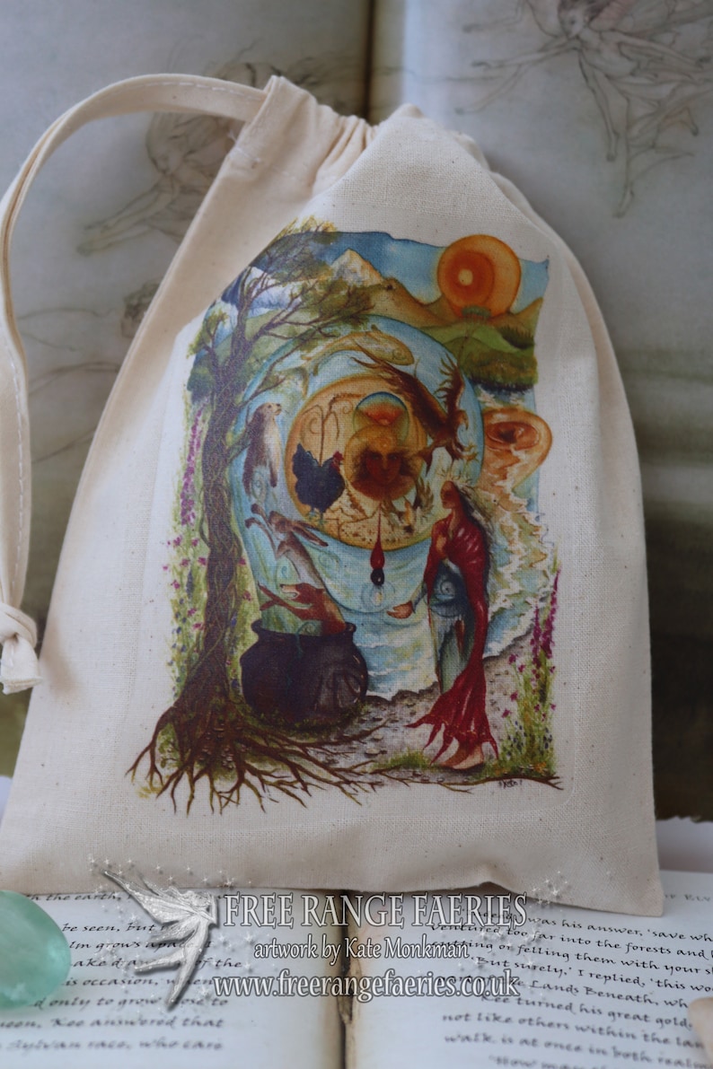May include: A white cotton drawstring bag with a colorful illustration of a woman standing in a forest with a cauldron, a tree, and a sun. The bag has the text "FREE RANGE FAERIES" and "artwork by Kate Monkman" printed on it. The text "www.freerangefaeries.co.uk" is also printed on the bag.