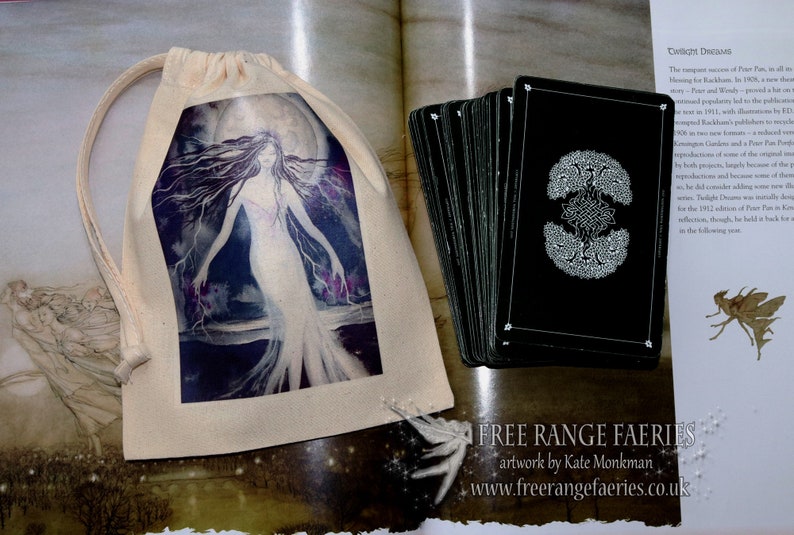 Puede incluir: Una bolsa de algod&oacute;n blanco con cord&oacute;n de ajuste, impresa con una imagen de una mujer de pie frente a una luna llena. La bolsa est&aacute; llena de una baraja de cartas negras con dise&ntilde;os blancos. El texto "FREE RANGE FAERIES artwork by Kate Monkman www.freerangefaeries.co.uk" est&aacute; impreso en la parte inferior de la imagen.