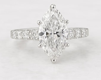 May include: A marquise-cut diamond engagement ring. The large, clear diamond is the focal point, set with six prongs. The band features smaller, round diamonds. The ring is set in a white metal, likely platinum or white gold.