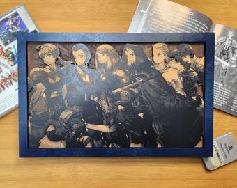 May include: A framed artwork featuring a group of stylized characters in a dark color palette. The artwork is set against a light brown background and framed in a dark blue frame. A video game case and manual are visible.