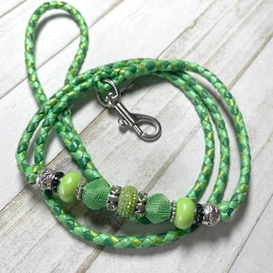 May include: Green braided leather dog leash with a silver clasp and green and silver beads.