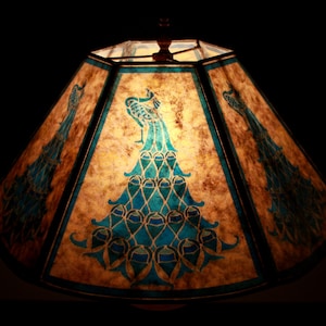 May include: A brown lampshade with a peacock design in shades of blue and green. The lampshade is made of paper and has a geometric shape.