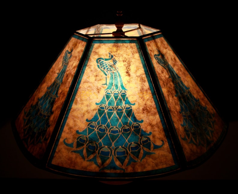 May include: A brown lampshade with a peacock design in shades of blue and green. The lampshade is made of paper and has a geometric shape.