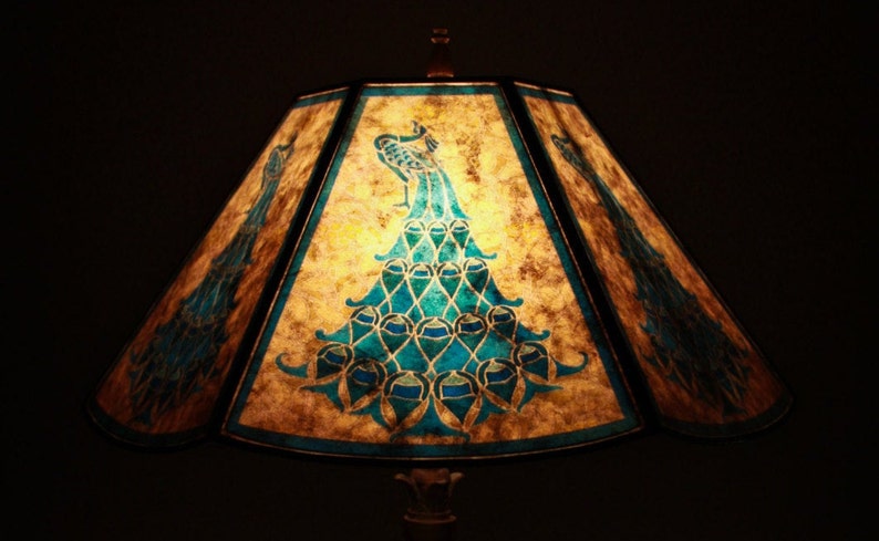 May include: A lampshade with a peacock design in shades of blue and green on a beige background.