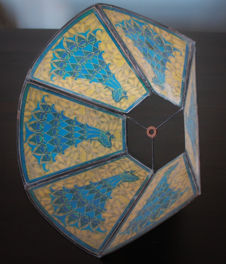 May include: A hexagonal lampshade with a geometric design featuring peacocks in shades of blue, green, and yellow on a white background.
