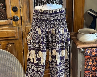 May include: Black and white patterned pants with a design of elephants. The pants are loose fitting and have a wide leg. The pants are made of a soft, flowing fabric.