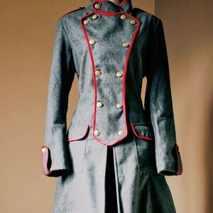 May include: A gray double-breasted coat with red trim and gold buttons. The coat has a long, flowing skirt and is cinched at the waist.