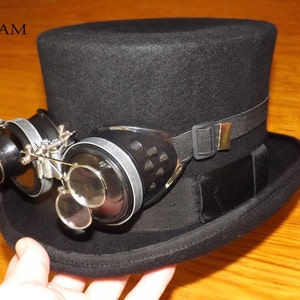 Peut inclure: Un chapeau haut de forme noir avec un bandeau &eacute;lastique noir et une paire de lunettes steampunk avec des verres grossissants.