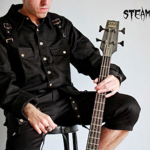 May include: A person wearing a black button-down shirt with straps and black pants, holding a black bass guitar. The word "STEAMRETRO" is written in black letters on a white background.