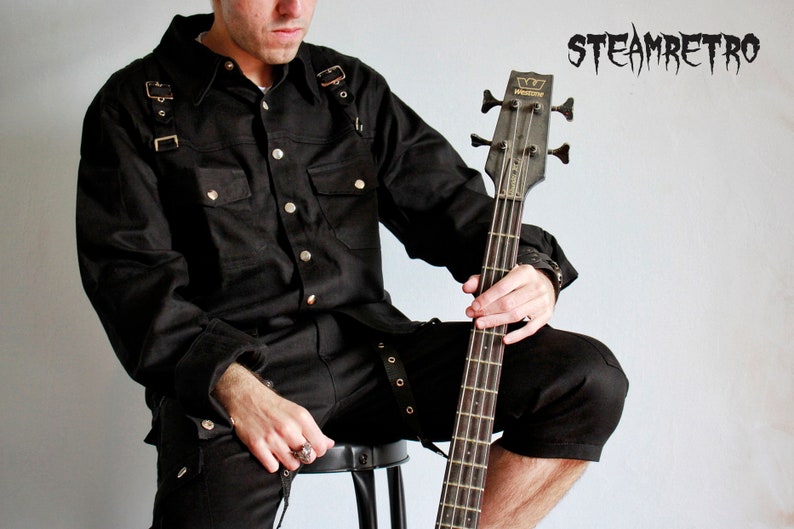 May include: A person wearing a black button-down shirt with straps and black pants, holding a black bass guitar. The word "STEAMRETRO" is written in black letters on a white background.