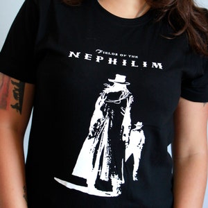 May include: Black t-shirt with a white graphic of a person in a long coat and hat. The text "Fields of the Nephilim" is printed on the shirt.