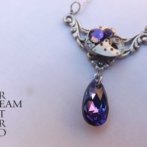 May include: A silver steampunk necklace with a purple crystal pendant. The necklace features a clockwork design with gears and a purple crystal.