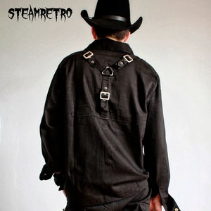 May include: Black long-sleeved shirt with a black leather harness featuring silver buckles. The shirt has a collar and a button closure. The harness has a triangular shape in the back.