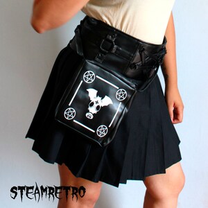 May include: A black pleated skirt with a black leather belt and a black leather pouch with a white gas mask and bat design. The pouch has a white border with five pentagrams.