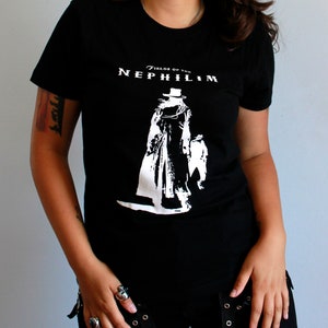 May include: Black t-shirt with a white graphic of a figure in a long coat and hat. The text "Fields of the Nephilim" is printed above the figure.