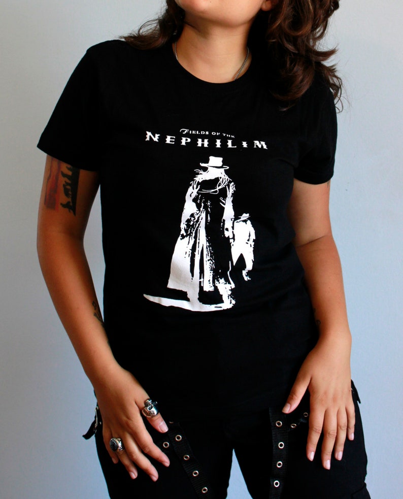May include: Black t-shirt with a white graphic of a figure in a long coat and hat. The text "Fields of the Nephilim" is printed above the figure.